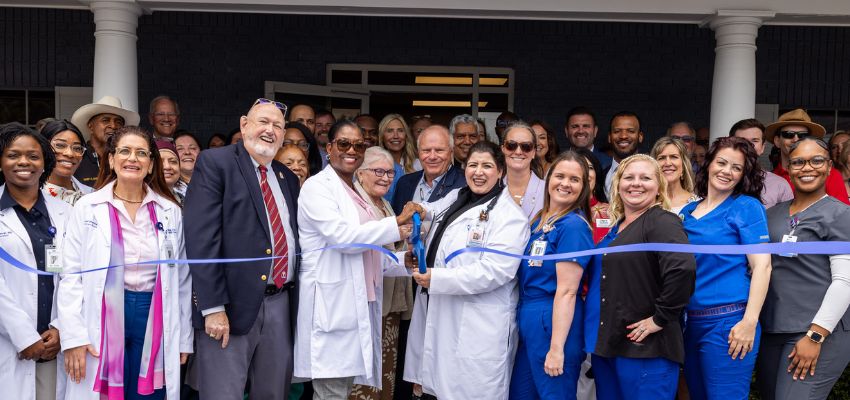 Faculty, physicians and community members gather for a ribbon-cutting ceremony celebrating the opening of a healthcare facility.