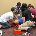 Medicalstudentsworktogetherduringanemergencyresponsesimulationtreatingapatientlyingonthefloorwithcervicalstabilizationequipmentnearby