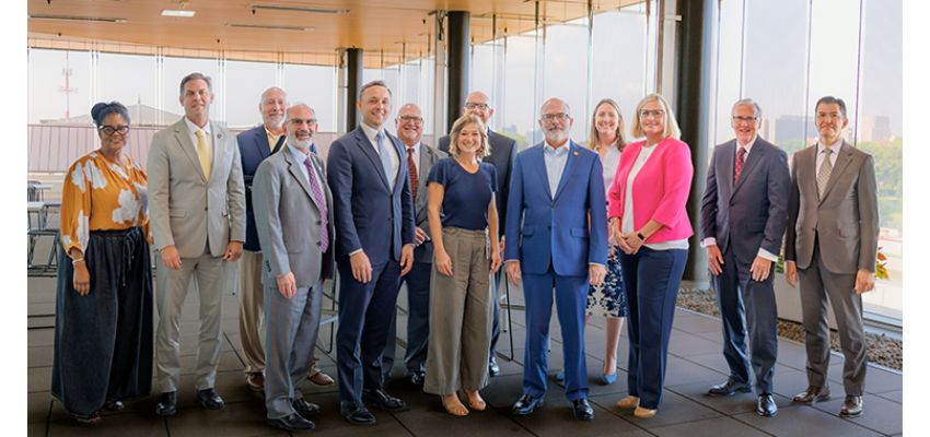 Kansas City University leaders and guests pose for a group photo during a meeting or partnership event.