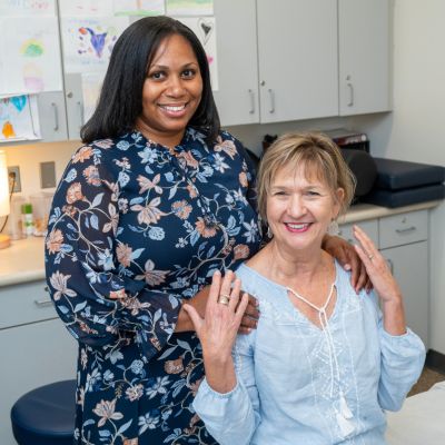A physician stands beside a smiling patient in an examination room during a clinical visit.