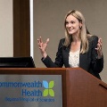 WomanspeakingatapodiumatCommonwealthHealthRegionalHospitalofScrantongesturingwithbothhandsduringapresentation
