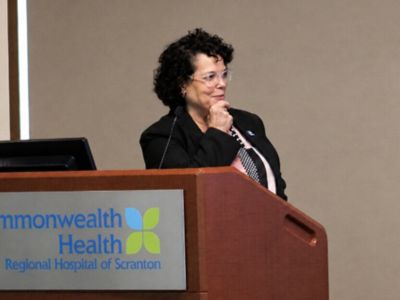 Woman speaking at a podium and gesturing toward the audience at Commonwealth Health Regional Hospital of Scranton.