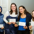 Fourstudentsposetogetherwhileholdingenvelopespresentedduringanawardsorrecognitionevent