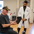 Aveteranwithaprostheticlegspeakswithtwohealthcareprofessionalsinarehabilitationfacility