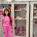 Astudentinpinkscrubsstandsbesidecabinetsdisplayinganatomicalmodelsinamedicallaboratory