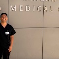 AmedicaltraineeinblackscrubsstandsinfrontofaUCLAMedicalCentersign