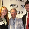 ThreeattendeesposetogetherinfrontofaStudentOsteopathicMedicalAssociationbackdropatanevent