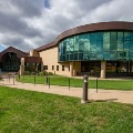 Exteriorviewofamedicalschoolbuildingfeaturingacurvedglassfacadesurroundedbywalkwaysandgreenlawn