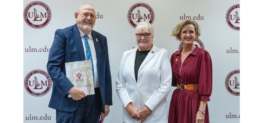 Three people pose together in front of a University of Louisiana Monroe backdrop.