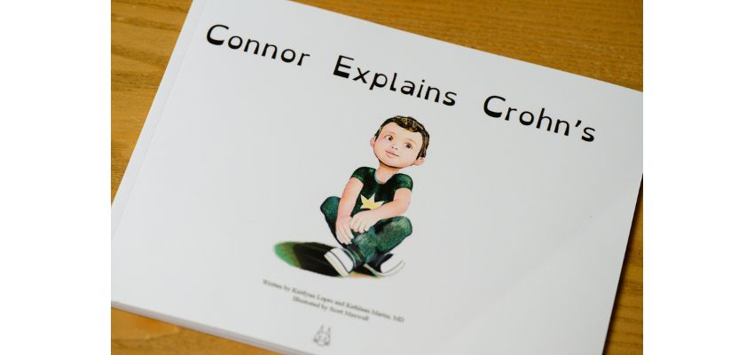 A children’s book titled “Connor Explains Crohn’s” rests on a wooden table.