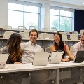 Fivestudentssittogetherwithtabletsinatieredclassroomsmilingandtalkingwithoneanother