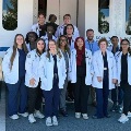 Agroupofmedicalstudentsandfacultyinwhitecoatsposesinfrontofamobilemedicalunit