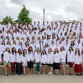 Alargegroupofmedicalstudentswearingwhitecoatsposestogetherinanoutdooramphitheater