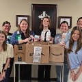 Agroupofstudentsandmedicalprofessionalsposeswithdonatedpersonalcareproductsandboxescollectedforacommunityserviceproject