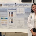 AmedicalstudentinawhitecoatstandsbesidearesearchposteronhypertensionrelatedcomplicationsamongFloridaparticipantsintheAllofUsResearchProgram
