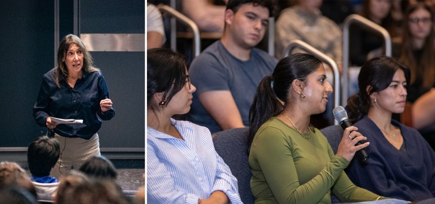 A speaker addresses an audience during a presentation while an attendee asks a question into a microphone.