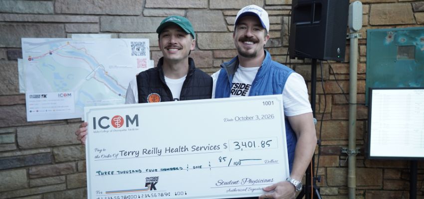 Two men hold a ceremonial check for $3,401.85 donated to Terry Reilly Health Services during an ICOM community fundraising event.
