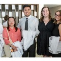 Sevenstudentsposetogetherholdingwhitecoatsduringanindoormedicalschoolevent