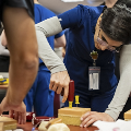 Amedicalstudentinbluescrubspracticesinsertinganeedleintoasimulationmodelduringahands-onclinicalskillstrainingsession