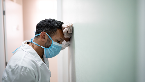 Exhausted physician leaning against a wall