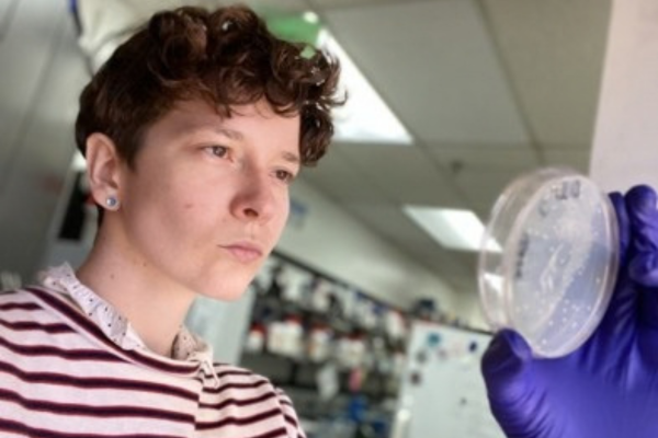 Dr. Adkins examining a petri dish in a lab setting.