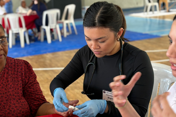 Negia performing a glucose monitoring test on a patient during the Dominican Republic medical outreach trip