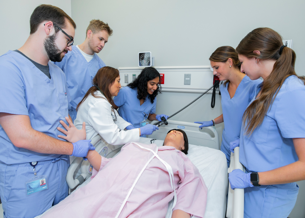 A professor teaching medical students how to test for head injury with a simulated patient