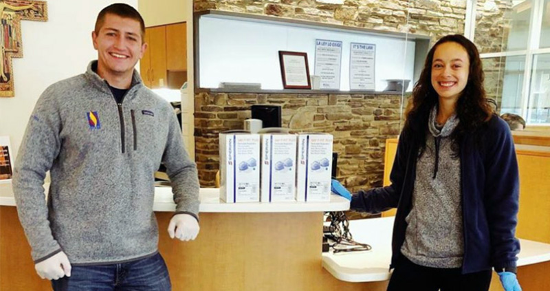 PCOM Students pose in front of fundraising marketing materials