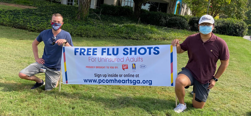 Students pose by Free Flu Shots for Uninsured Adults sign