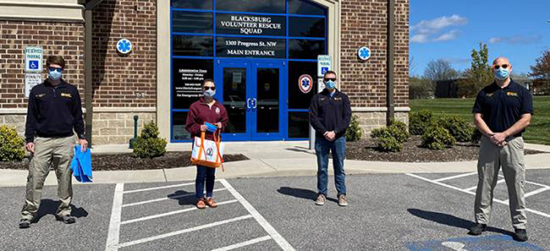 Four volunteers in masks pose in front of Blacksburg Volunteer Rescue Squad building