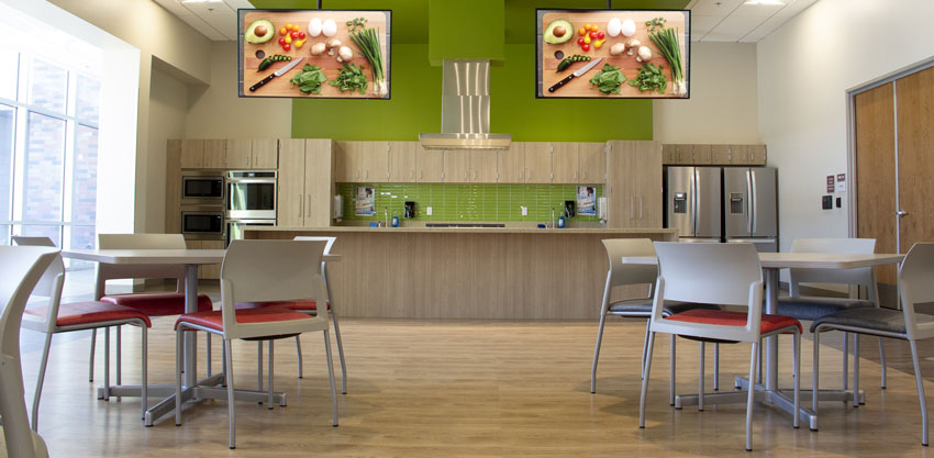 Dining hall kitchen with TVs showing healthy food choices