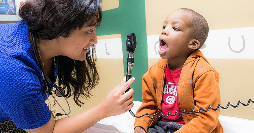 Female doctor checking young boy's throat