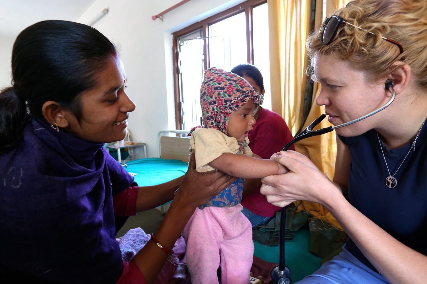 Female med student examines infant in clinic setting.