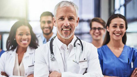 Group of smiling doctors in white coats and scrubs