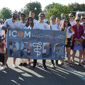 ICOMstudentswearingrainbowt-shirtsandholdinganICOMbanner