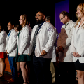 Studentsstandonstagewhilereceivingwhitecoats