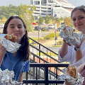 Studentsstandonbalconywhileeatingbagels