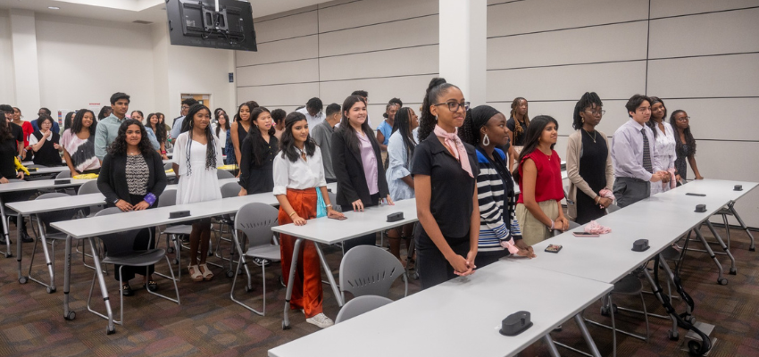 Students standing in a classroom, participating in an educational event.