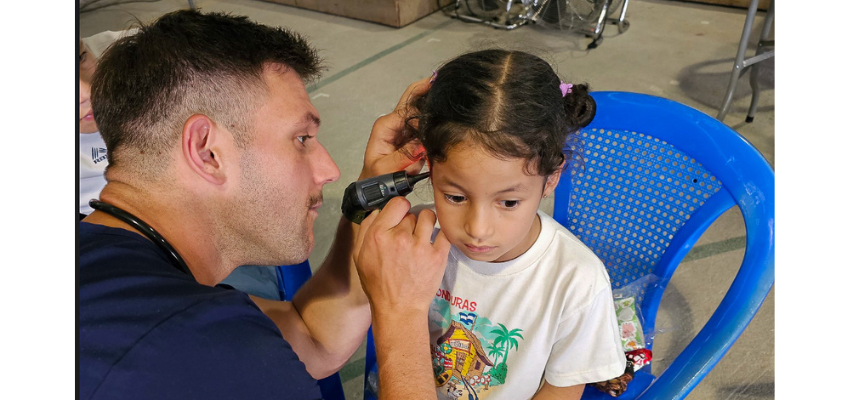 A healthcare professional examining a young girl's ear with an otoscope.